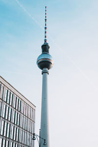 Low angle view of communications tower against sky in city