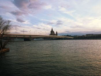 Bridge over river against cloudy sky