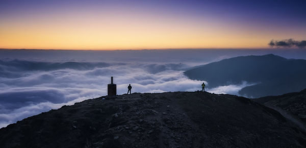 Silhouette building on mountain against sky during sunset