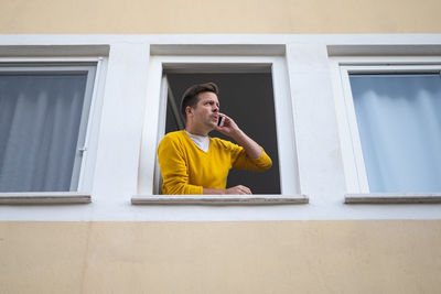 Portrait of young man looking through window