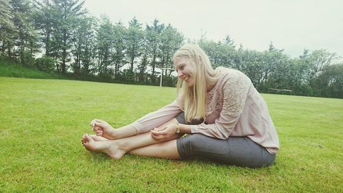 Smiling woman applying nail polish on toenails at park