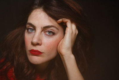 Close-up portrait of beautiful woman against black background