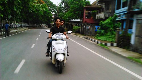 Friends riding motor scooter on street