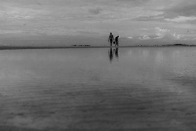People standing in sea against sky