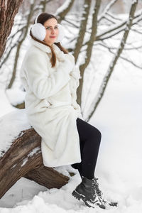 Portrait of young woman sitting on snow