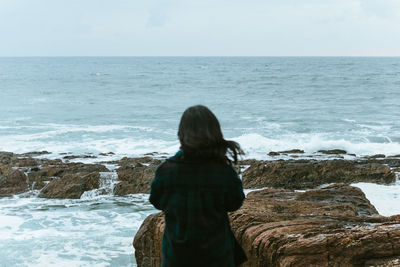 Rear view of man looking at sea against sky