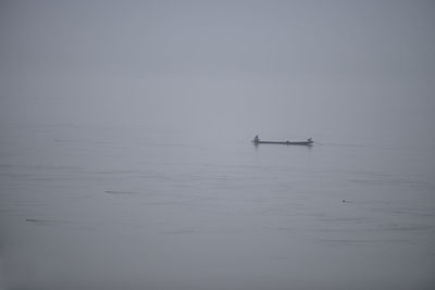 Silhouette people on boat in sea against sky