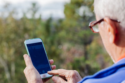 Rear view of old man taking a photo with his mobile phone