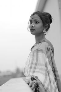 Side view of thoughtful woman wearing sari standing against clear sky