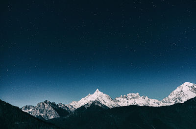 Scenic view of snowcapped mountains against sky at night