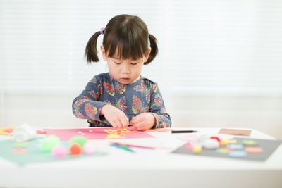 Cute girl playing with ball on table