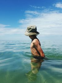 Shirtless boy swimming in sea against sky