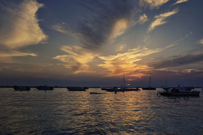 Silhouette sailboats in sea against sky during sunset