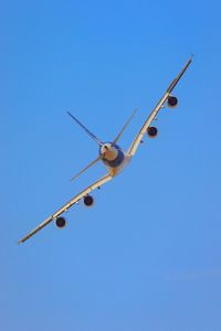 Low angle view of airplane against clear blue sky