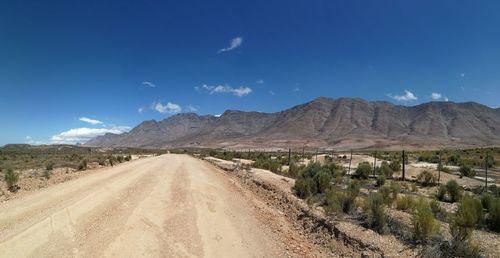 Road amidst landscape against blue sky