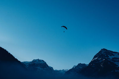 Low angle view of people in mountains against clear blue sky