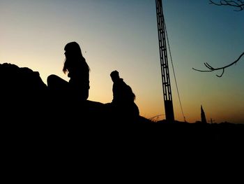 Low angle view of silhouette people by pole against sky during sunset