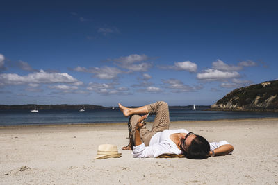 Woman using mobile phone relaxing at beach on sunny day