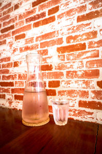Wine glass on table against brick wall