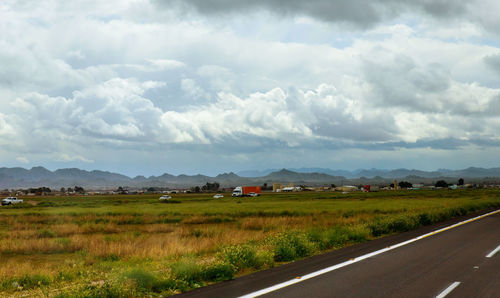 Road amidst field against sky