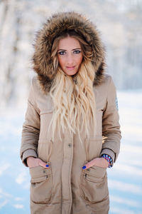 Portrait of young woman wearing warm clothing standing in forest