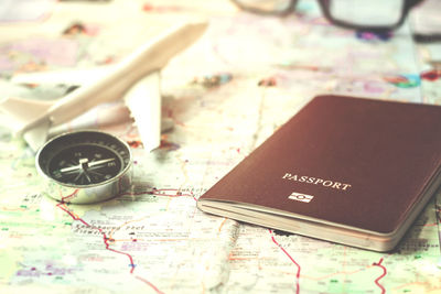 High angle view of navigational compass and passport on world map