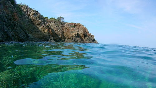 Rock formation in sea against sky