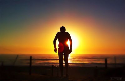 Silhouette of couple standing on sea at sunset