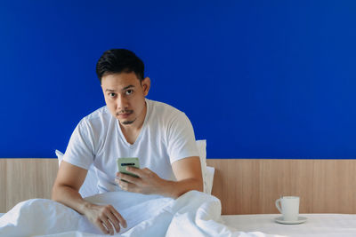 Mid adult man holding coffee while sitting on table