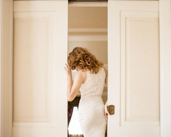 Woman with blond hair wearing dress standing at doorway