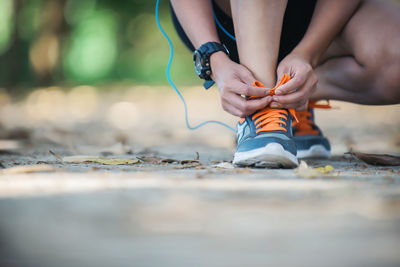 Low section of woman tying shoelace on footpath