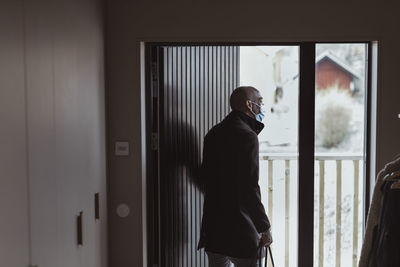 Businessman wearing protective face mask walking through door during covid-19