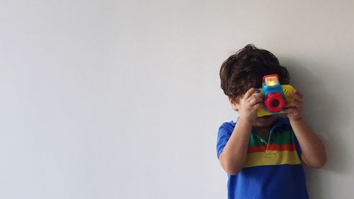 Boy holding camera over white background