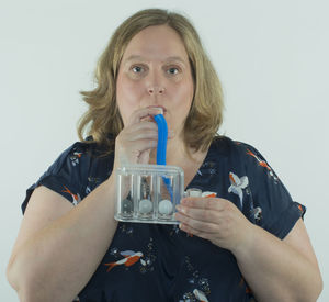 Portrait of beautiful young woman drinking water against white background