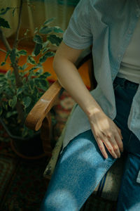 Midsection of woman sitting on chair at home