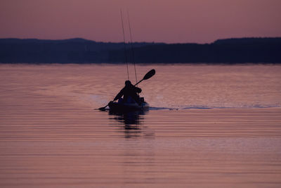 Silhouette man fishing in sea against sky during sunset