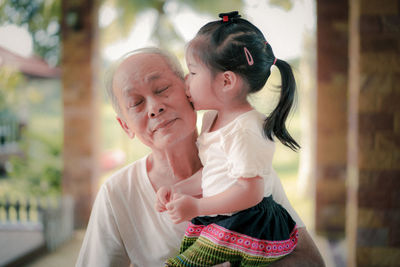 Granddaughter kissing grandfather at home