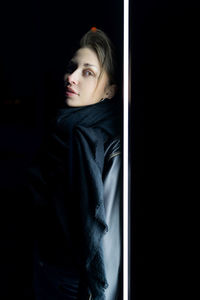 Portrait of young woman against black background