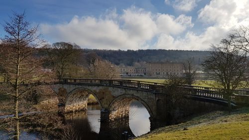 Arch bridge over river against sky