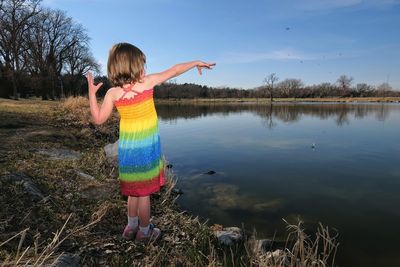 Rear view of girl gesturing towards river