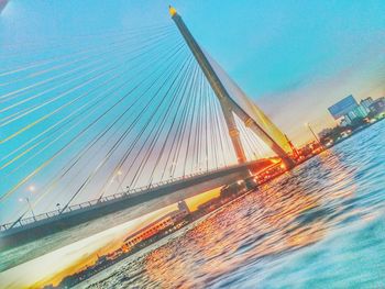 Suspension bridge over sea against sky in city