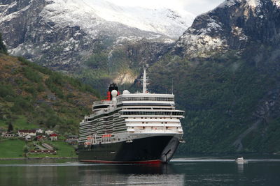 People on boat sailing on sea by mountain