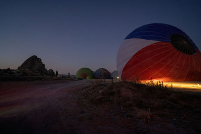 View of hot air balloons on field at sunset