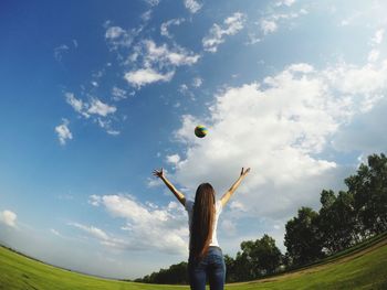 Low angle view of woman playing with ball against sky