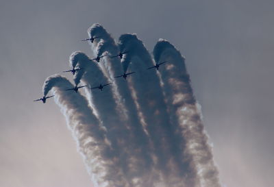 Low angle view of airplanes with trails in flight