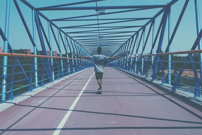 Rear view of woman walking on footbridge in city