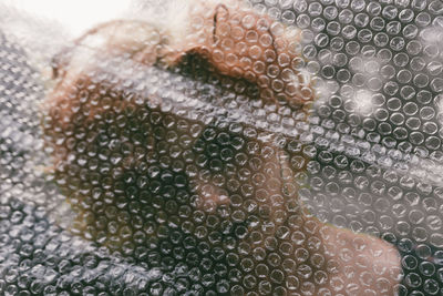 Woman seen through bubble wrap plastic foil