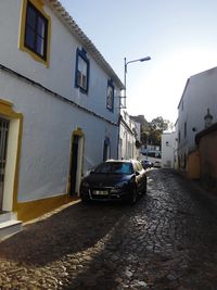 Cars on street amidst houses against sky