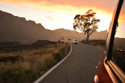 Road by mountain against sky during sunset