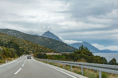 Road leading towards mountains against sky